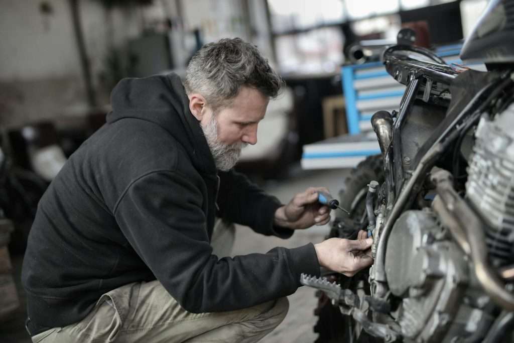 Focused mechanic working on motorcycle repair in a garage setting.